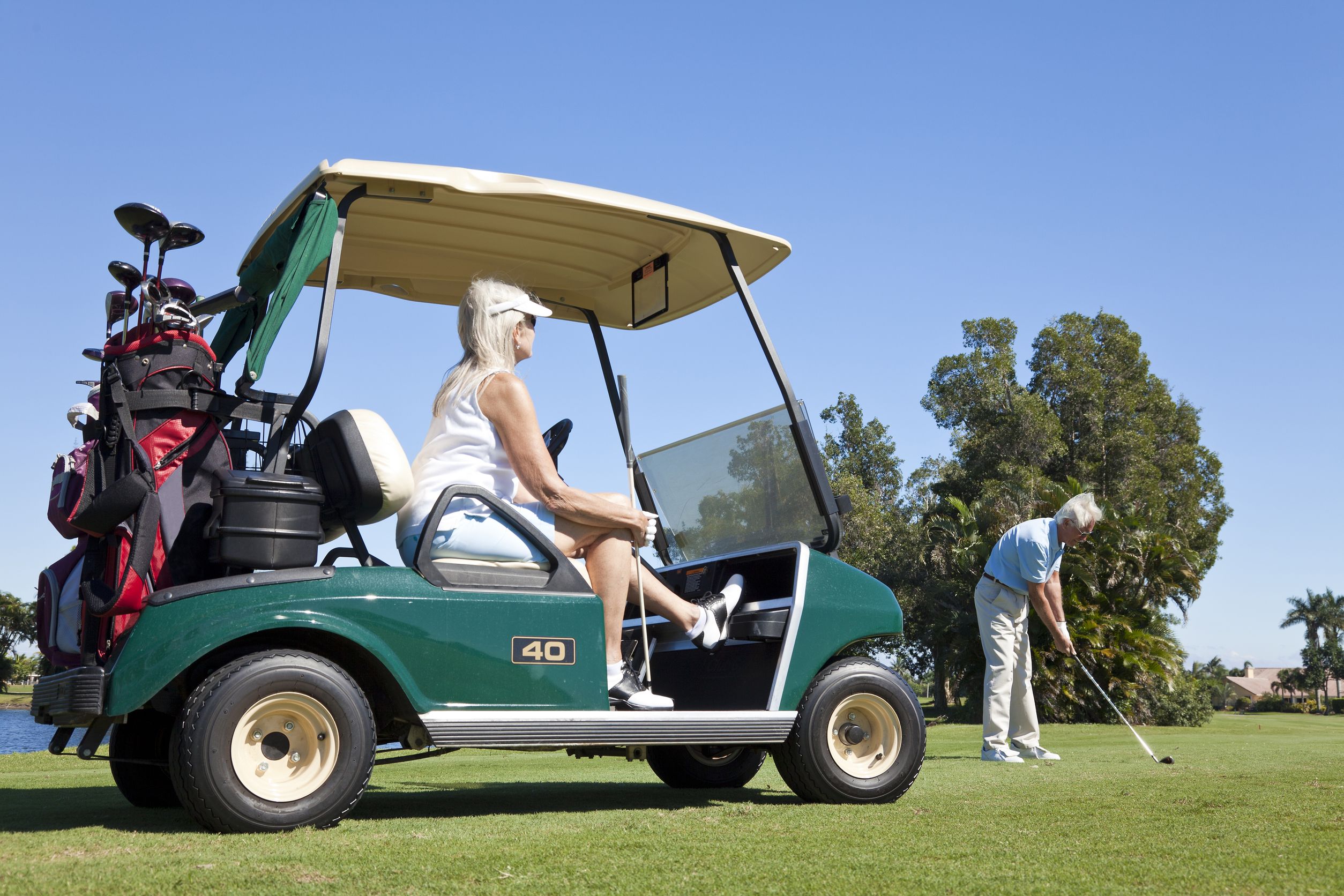 19524539_l-Happy-senior-man-and-woman-couple-together-playing-golf-the-man-is-hitting-a-shot-the-woman-is-sitting-in-a-golf-cart