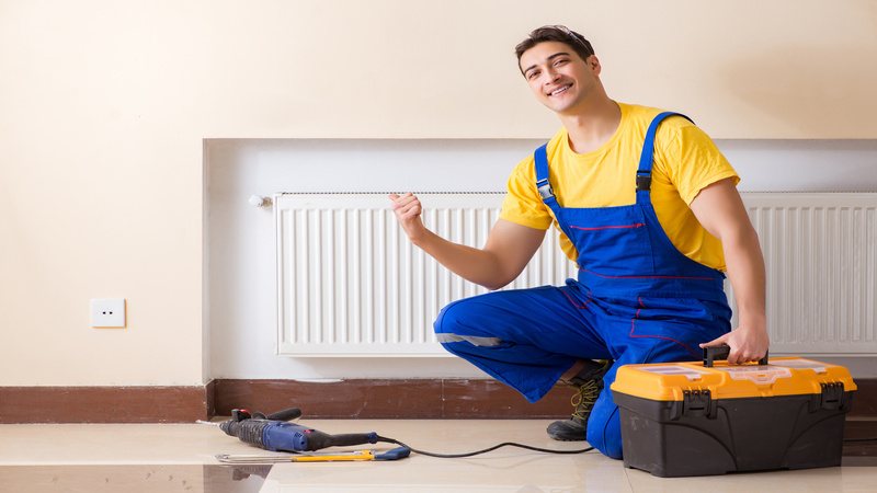 Young repairman contractor repairing heating panel