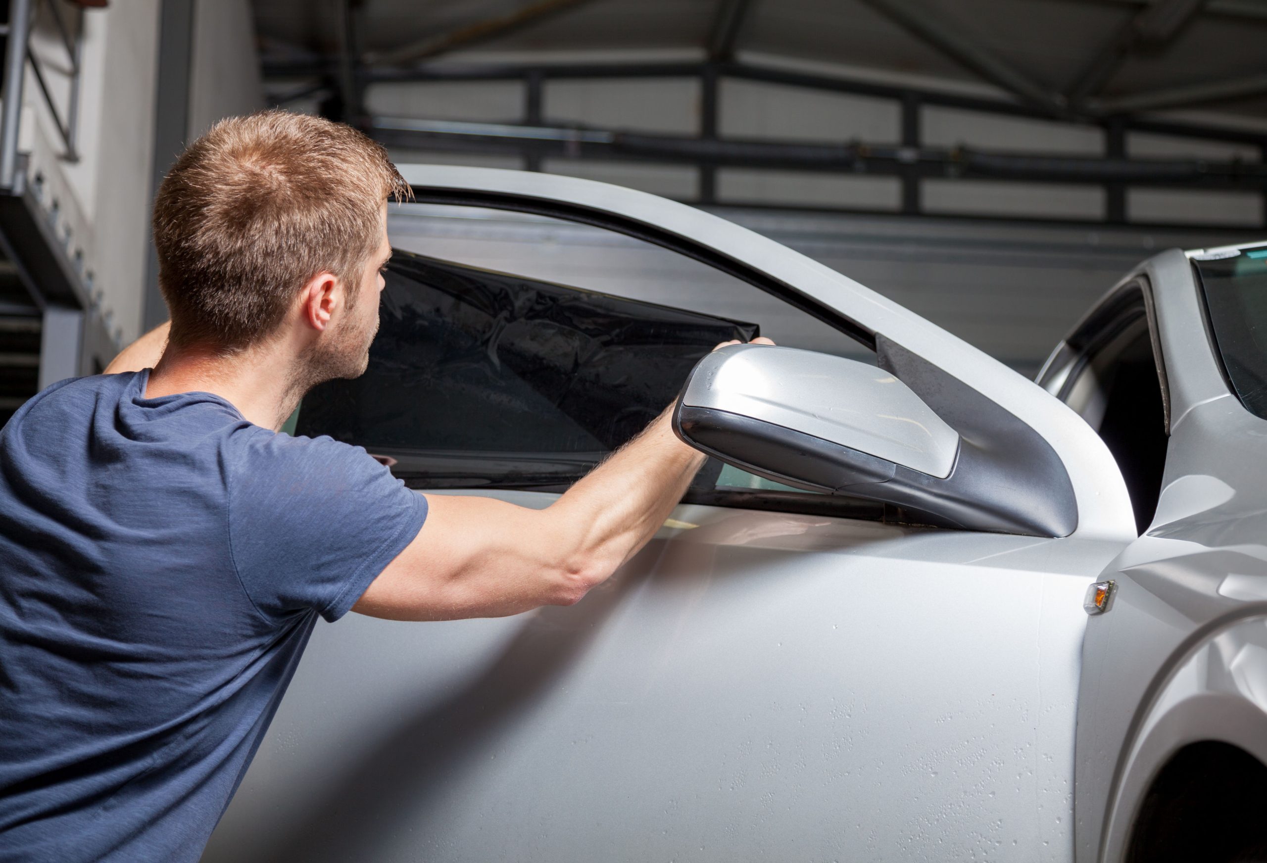 43583312 – applying tinting foil on a car window in a garage